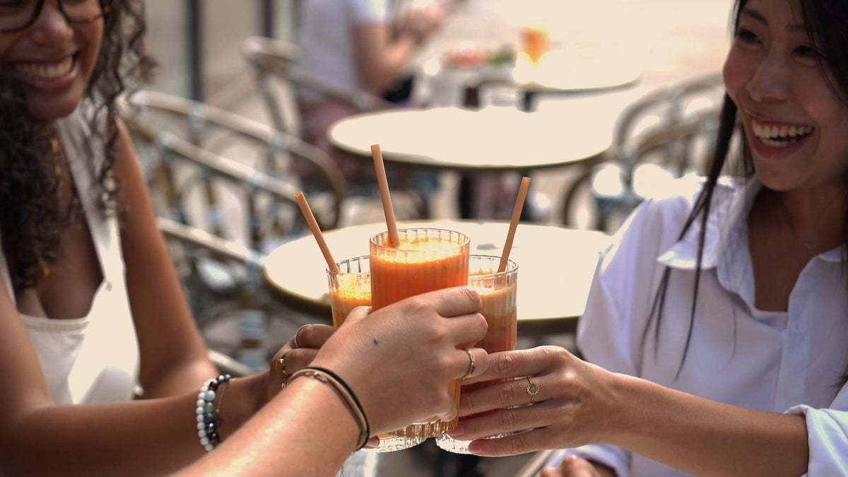 Deux amies trinquent avec des jus de fruits frais en terrasse